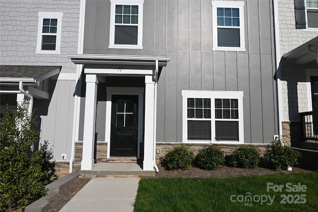 view of exterior entry featuring board and batten siding and stone siding