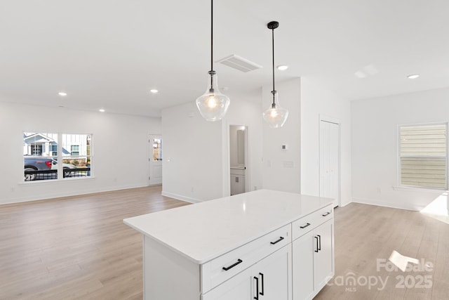 kitchen featuring white cabinetry, a kitchen island, pendant lighting, and light wood-type flooring