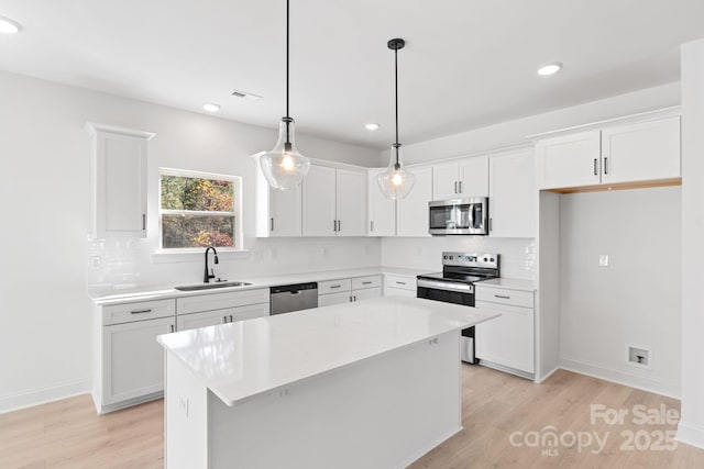 kitchen with sink, decorative light fixtures, a center island, stainless steel appliances, and white cabinets