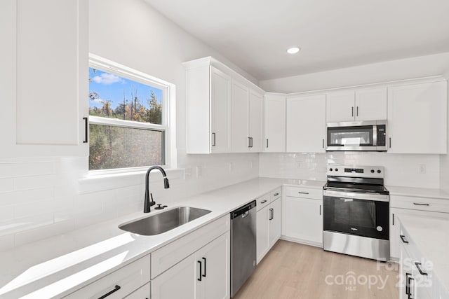 kitchen featuring white cabinetry, sink, stainless steel appliances, and light hardwood / wood-style floors