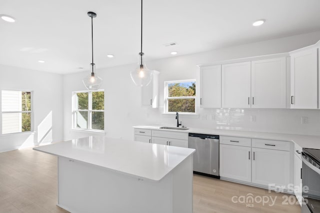 kitchen featuring sink, white cabinetry, hanging light fixtures, stainless steel appliances, and a center island