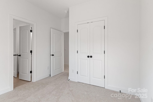 unfurnished bedroom featuring a closet and light carpet