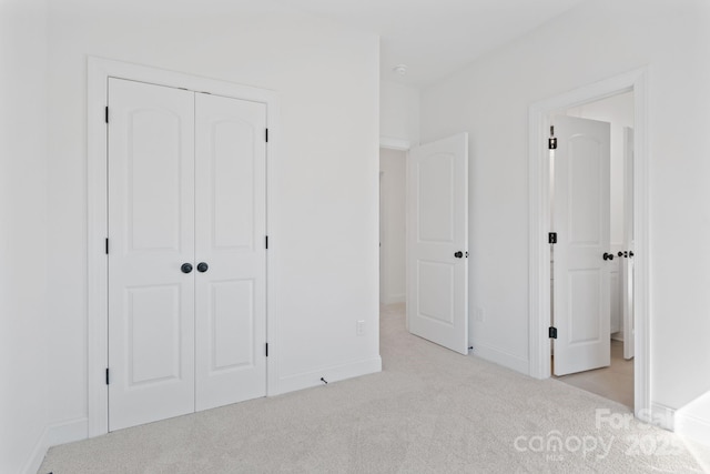 unfurnished bedroom with light colored carpet and a closet