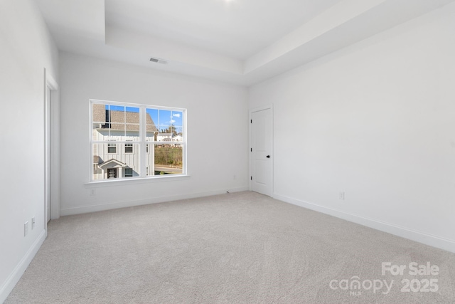 empty room with a raised ceiling and carpet flooring