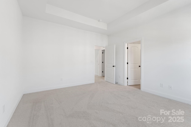 carpeted empty room with a tray ceiling