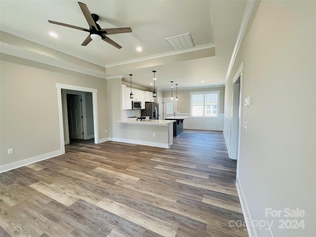 unfurnished living room featuring ceiling fan, wood-type flooring, and ornamental molding