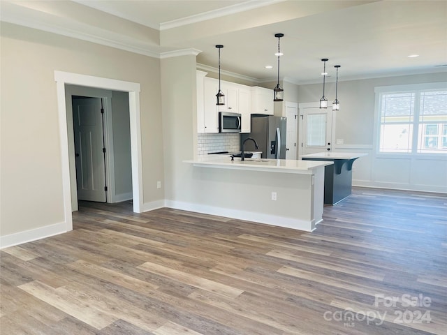 kitchen featuring pendant lighting, white cabinets, light hardwood / wood-style flooring, appliances with stainless steel finishes, and a kitchen bar