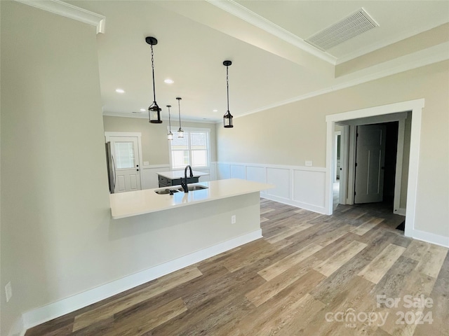 kitchen with stainless steel fridge, ornamental molding, sink, pendant lighting, and light hardwood / wood-style flooring