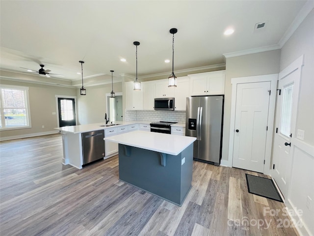 kitchen featuring kitchen peninsula, stainless steel appliances, ceiling fan, sink, and white cabinetry