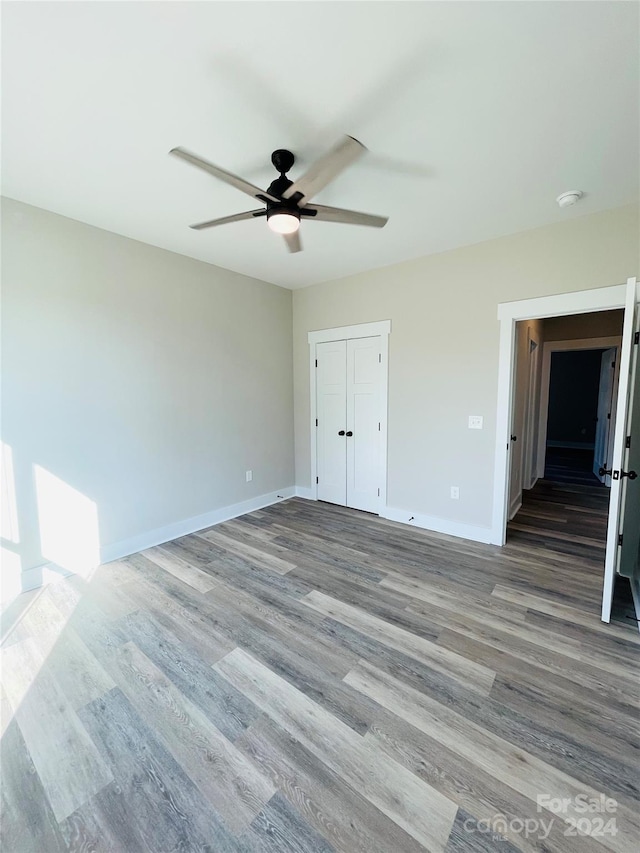 unfurnished bedroom featuring hardwood / wood-style flooring, ceiling fan, and a closet