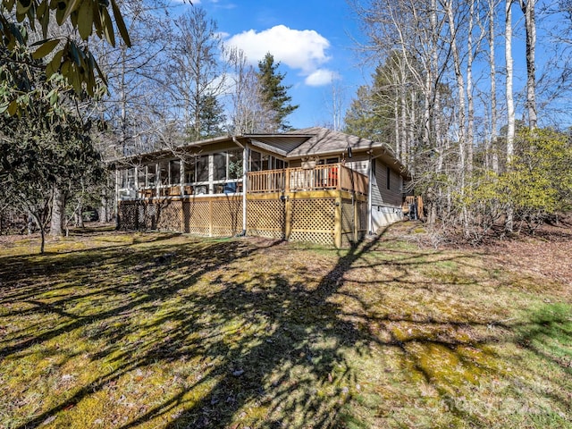 rear view of house with a wooden deck, a sunroom, and a lawn