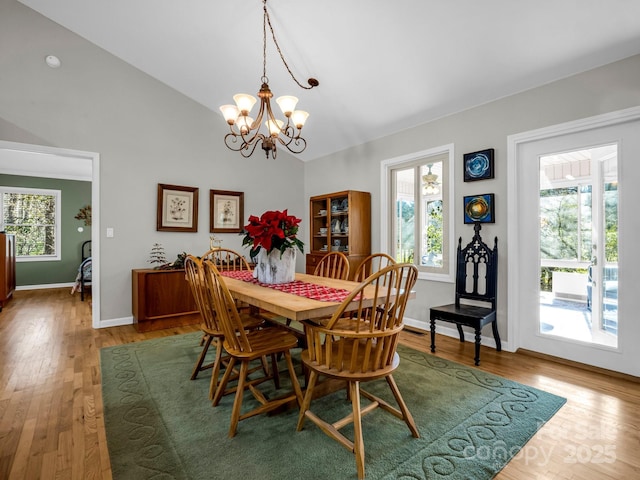 dining space featuring lofted ceiling, hardwood / wood-style floors, and an inviting chandelier