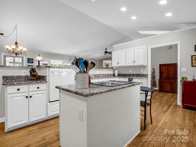 kitchen with lofted ceiling, a center island, light hardwood / wood-style floors, white cabinets, and decorative light fixtures