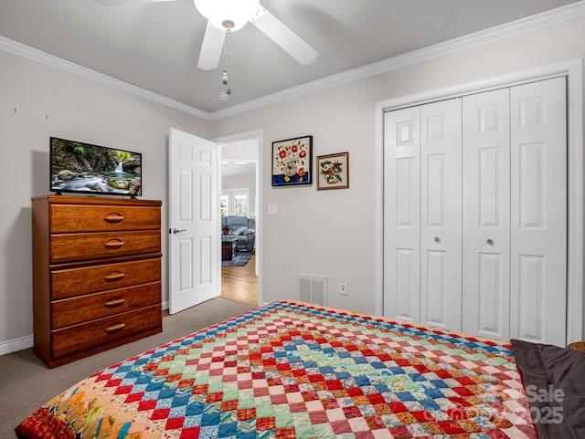 bedroom with ceiling fan, ornamental molding, carpet flooring, and a closet