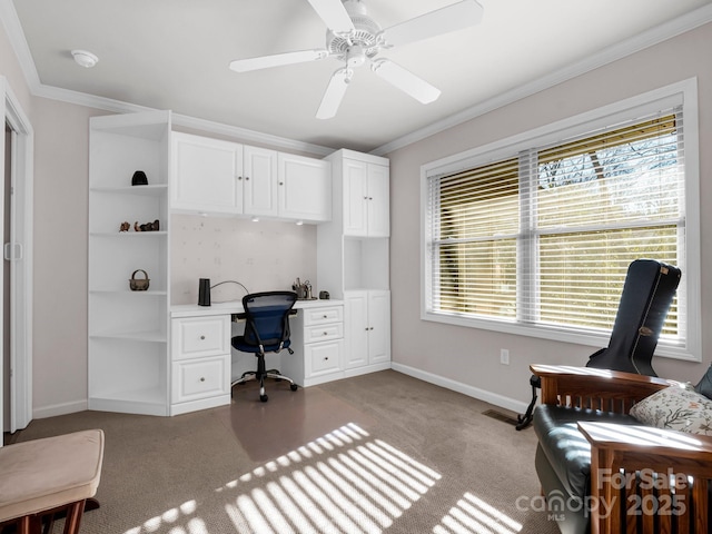 carpeted office with built in desk, ornamental molding, and ceiling fan