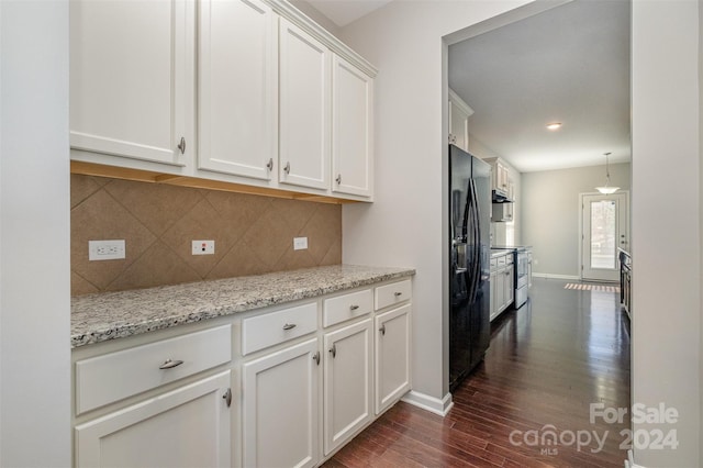 kitchen with light stone countertops, tasteful backsplash, black refrigerator with ice dispenser, dark hardwood / wood-style floors, and white cabinets