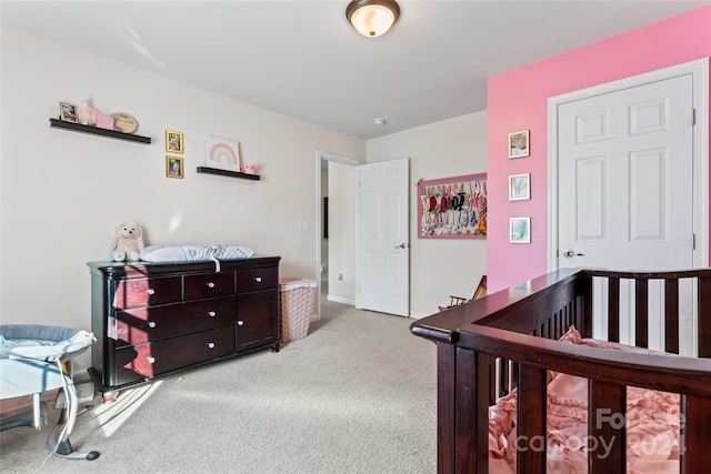 bedroom with light carpet and a nursery area