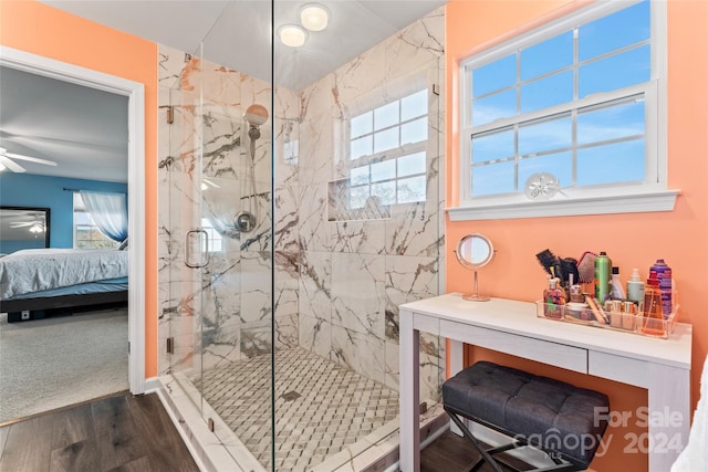 bathroom with ceiling fan, plenty of natural light, hardwood / wood-style floors, and a shower with shower door