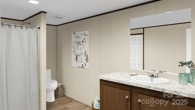 bathroom with vanity, crown molding, toilet, a textured ceiling, and wood-type flooring