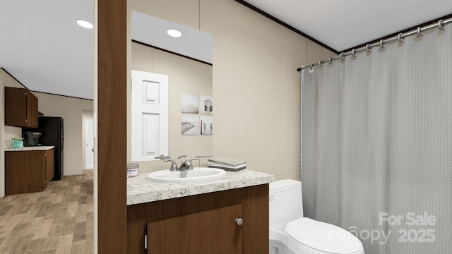 bathroom with vanity, a textured ceiling, hardwood / wood-style floors, toilet, and lofted ceiling