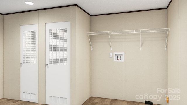 clothes washing area featuring hookup for a washing machine, a textured ceiling, crown molding, and hardwood / wood-style floors