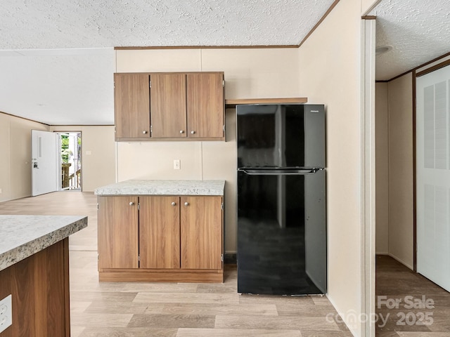 20 Windy Mountain Ln Unit 1, Hendersonville, NC 28792 - kitchen with freestanding refrigerator, a textured ceiling, light countertops, light wood-type flooring, and brown cabinetry