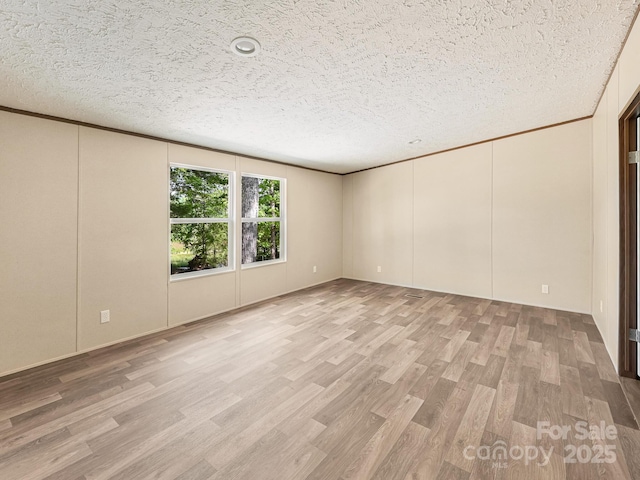 20 Windy Mountain Ln Unit 1, Hendersonville, NC 28792 - empty room featuring light wood-style floors, a textured ceiling, ornamental molding, and a decorative wall