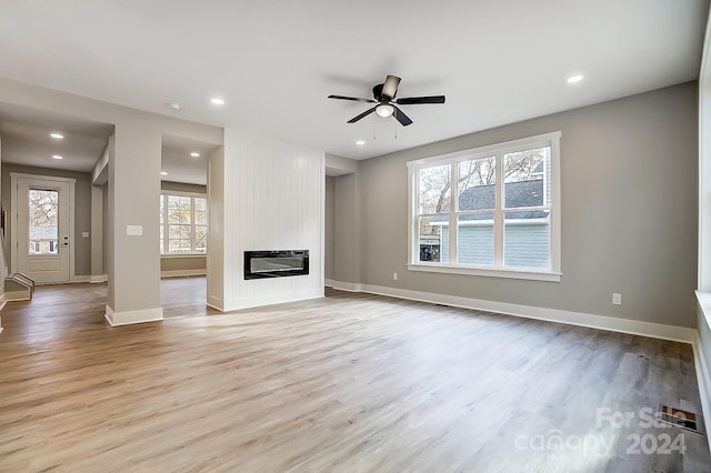 unfurnished living room featuring a healthy amount of sunlight, a fireplace, and light hardwood / wood-style flooring