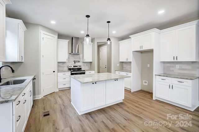 kitchen featuring a center island, sink, wall chimney exhaust hood, white cabinetry, and stainless steel appliances