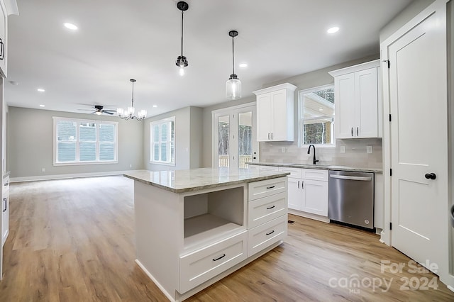 kitchen with pendant lighting, white cabinets, ceiling fan with notable chandelier, stainless steel dishwasher, and a kitchen island