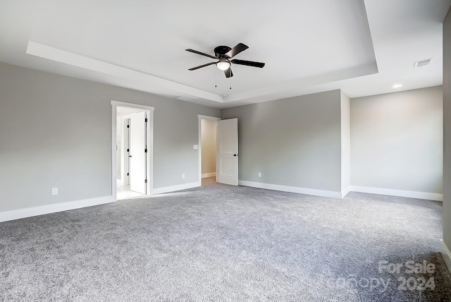 carpeted empty room with a raised ceiling and ceiling fan