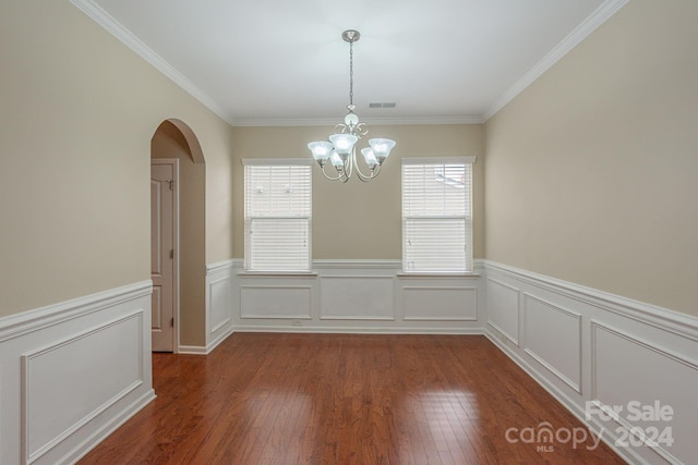 unfurnished dining area with dark hardwood / wood-style floors, ornamental molding, and an inviting chandelier