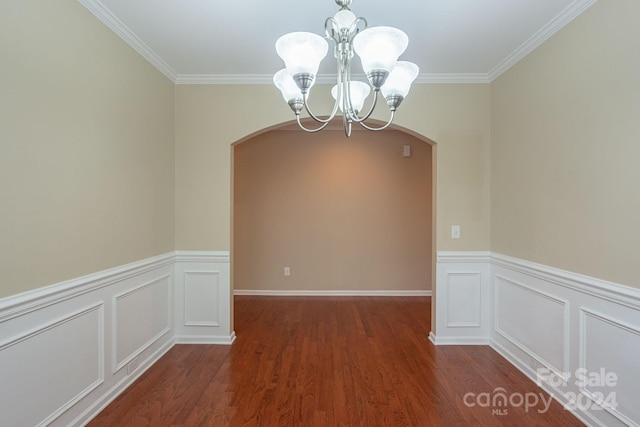 unfurnished room featuring dark hardwood / wood-style flooring, ornamental molding, and an inviting chandelier