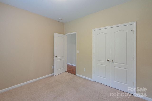 unfurnished bedroom featuring a closet and light colored carpet