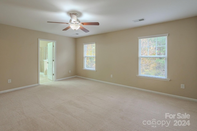 unfurnished room with light colored carpet, ceiling fan, and a healthy amount of sunlight