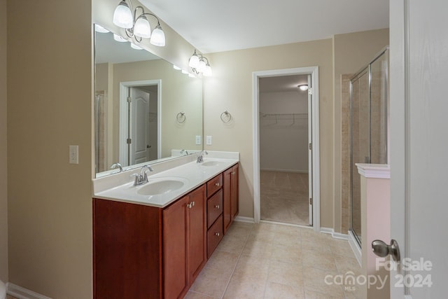 bathroom with a shower with door, vanity, and tile patterned flooring