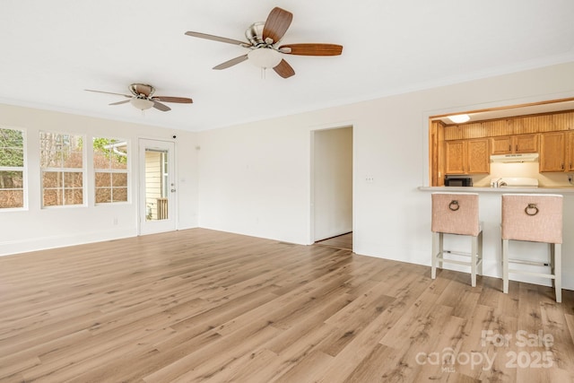 unfurnished living room featuring light wood-type flooring, ceiling fan, and ornamental molding