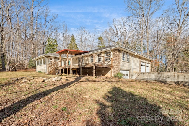 back of property featuring a lawn, a sunroom, a garage, and a deck