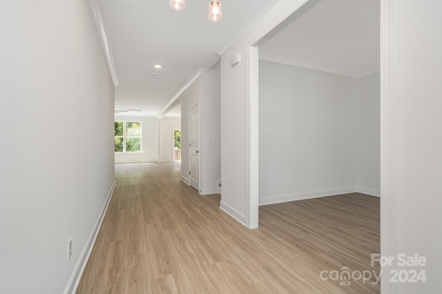 corridor with ornamental molding and light hardwood / wood-style flooring