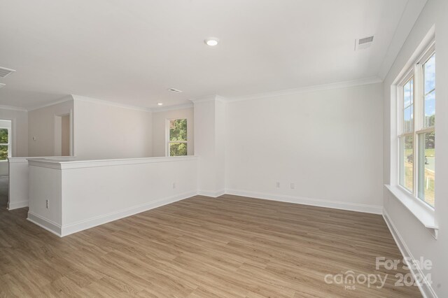 spare room featuring wood-type flooring and crown molding