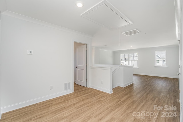 empty room with ornamental molding and light wood-type flooring