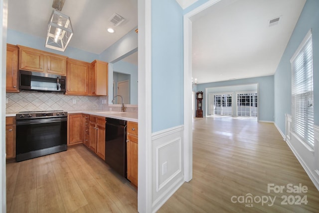 kitchen with sink, stainless steel appliances, a notable chandelier, backsplash, and light hardwood / wood-style floors