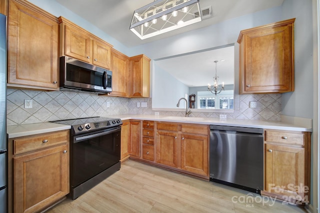 kitchen with pendant lighting, an inviting chandelier, decorative backsplash, light wood-type flooring, and appliances with stainless steel finishes