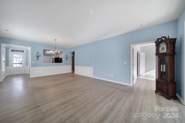 unfurnished living room featuring light hardwood / wood-style floors and a notable chandelier