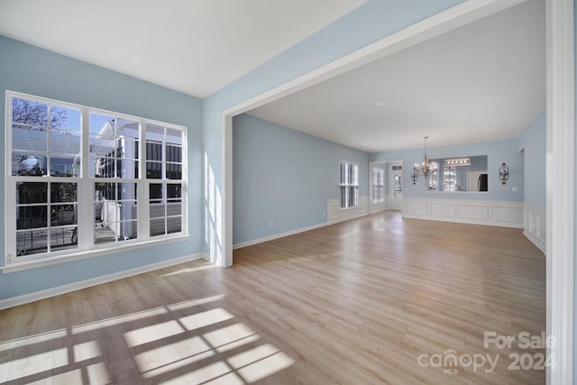 unfurnished living room featuring a chandelier and light wood-type flooring