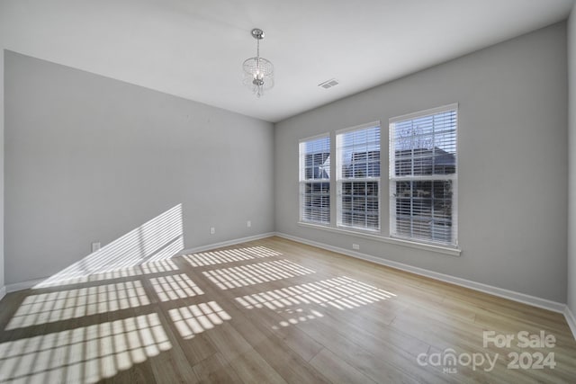 unfurnished room with a chandelier and light hardwood / wood-style flooring