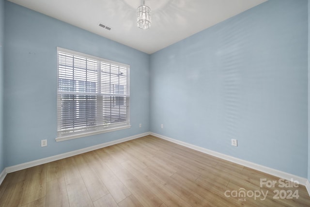 spare room featuring a chandelier and light wood-type flooring