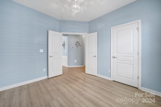 unfurnished bedroom featuring a chandelier and light hardwood / wood-style floors