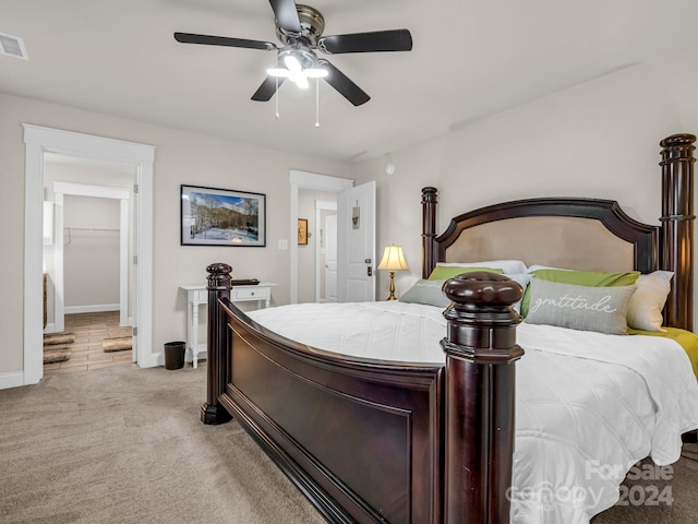 carpeted bedroom with ceiling fan and a walk in closet