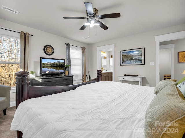 carpeted bedroom featuring ensuite bathroom, ceiling fan, and multiple windows